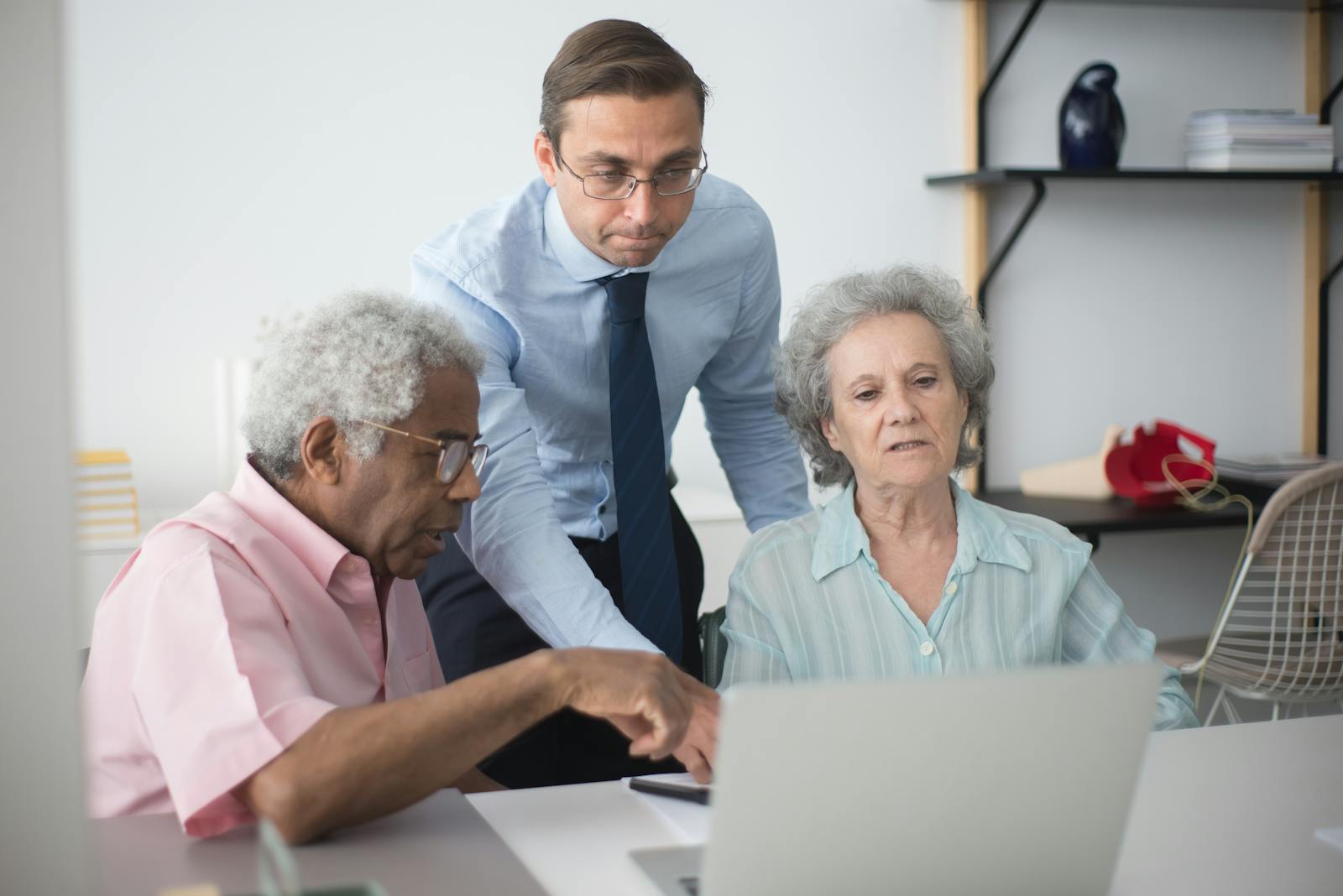 Senior couple consulting with a business agent at home on a laptop.